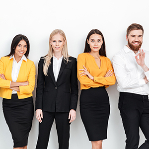 A group of professional millennials leaning up against the walk smiling and excited to work.