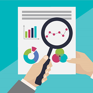 Human holding magnifying glass looking at charts and graphs